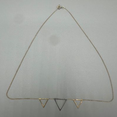 un gros plan d'un collier en forme de triangle monté sur une chaîne
