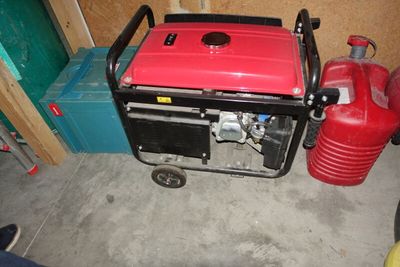 un petit générateur rouge posé dans un garage, à côté d'une borne d'incendie rouge