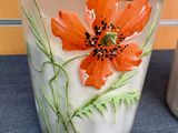 a vase with a flower painted on it sitting on a table