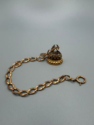 a close up of a gold chain with a bird on it