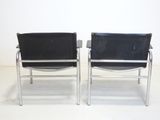 pair of chrome and black leather lounge chairs with armrests