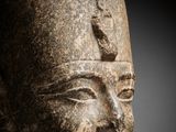 a close up of a stone head of a person wearing a helmet