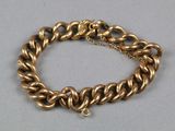 gros plan d'un bracelet en chaîne en or sur une surface grise