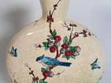 a white vase with a blue bird and flowers on it