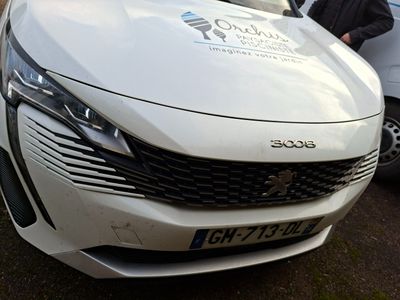 un homme debout à côté d'une voiture blanche garée sur le bord de la route