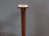 a wooden pedestal with a marble top in the corner of a room