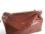brown leather purse with brass hardware on top of a white table