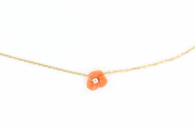 un collier en or orné d'une fleur orange, monté sur une chaîne en or