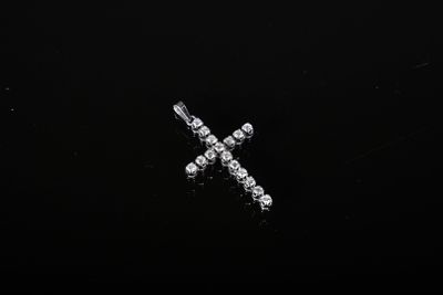 un gros plan d'une croix en diamant sur une surface noire