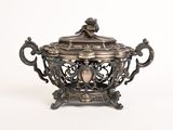 un plat ancien en argent orné d'un oiseau, posé sur un socle