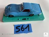 une petite voiture bleue posée sur un plateau vert