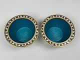 two blue bowls with gold rims are sitting on a white surface