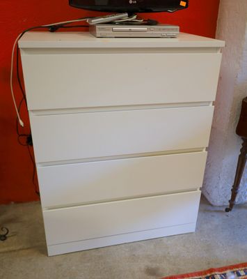 une commode blanche sur laquelle est posée une télévision à écran plat