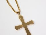 a gold cross pendant with a chain on a white background