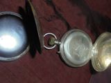 une montre de poche en argent posée sur une table rouge