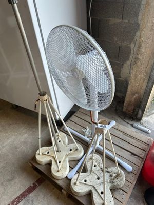 a fan that is sitting on a pallet next to a fire hydrant