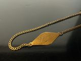 a gold necklace with a leaf on it on a table