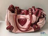 Quelqu'un tient un sac à main rose et rouge orné d'un cœur.