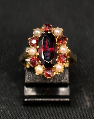 une image d'une bague ornée d'un grenat et de perles