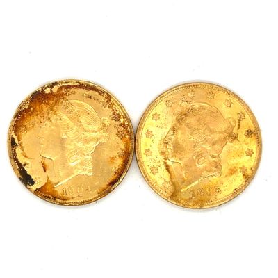 Deux pièces d'or sont posées côte à côte sur une surface blanche