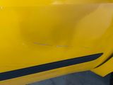 the side of a yellow car with a black stripe on it
