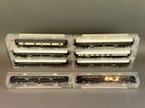 three model train cars in plastic boxes on a table