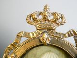 un cadre doré dans lequel figure le portrait d'une femme portant une couronne