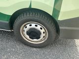 une petite voiture verte avec un pneu crevé dans la rue