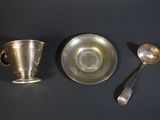 two silver cups and a spoon on a table