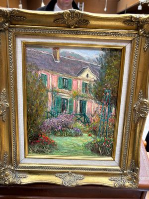 une photo d'un tableau représentant une maison, posé sur une table