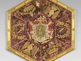 an image of a red and gold plate with a coat of arms on it