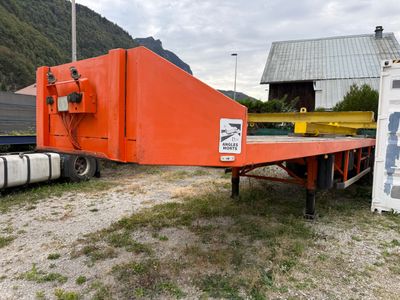une remorque à plateau de couleur orange garée dans un champ