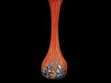an orange glass vase with blue and white flowers in it on a black background