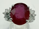 a close up of a ring with a red stone surrounded by white diamonds