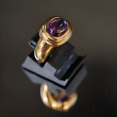 Gros plan sur une bague en or ornée d'une pierre violette.