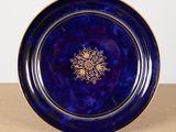 a close up of a blue and gold plate on a table