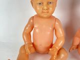two baby dolls sitting next to each other on a white surface