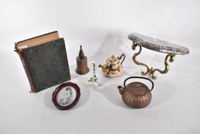 une table sur laquelle se trouvent un livre, une théière, une horloge et un autre livre