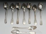 six cuillères et deux cuillères en argent sur une surface blanche
