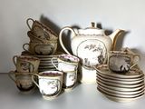 many cups and saucers and a teapot on the table
