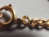 a close up of a gold bracelet on a white surface