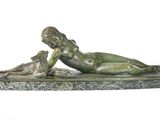 bronze statue of a boy laying on a rock with a dog