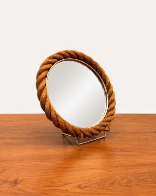 un miroir posé sur une table en bois, entouré d'une corde