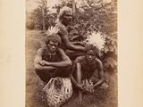 an old black and white photo of a group of people sitting on the grass