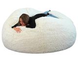 une femme allongée sur un pouf blanc, sur fond blanc