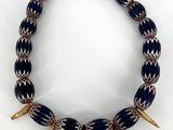 un collier bleu et blanc orné de pointes dorées sur fond blanc