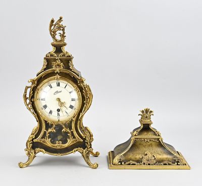 an antique clock and a small clock stand on a white surface