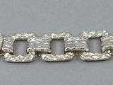 a close up of a silver bracelet on a gray surface