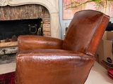 a brown leather chair sitting in front of a fire place