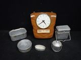une horloge en bois et des boîtes en fer-blanc posées sur une table noire